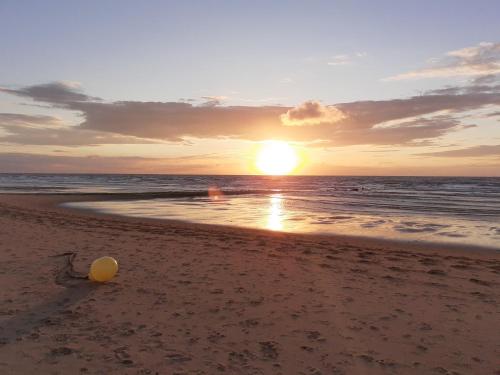 una puesta de sol en la playa con una pelota en la arena en Appartement Studio Wenduine, en De Haan