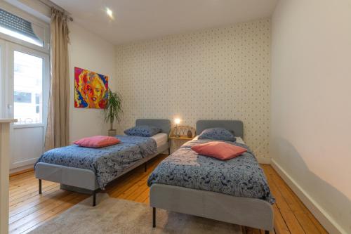 - une chambre avec 2 lits avec des couvertures bleues et une fenêtre dans l'établissement Plumeria - Grand Appartement 75m2 - Au calme - Proche Gare, Nouvelle Ville - Parking Public Gratuit - 2 Chambres - 4 Lits séparés, à Metz