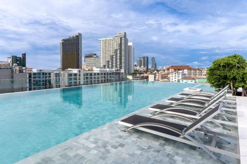 una piscina en la azotea de un edificio con tumbonas en Amethyst Hotel Pattaya, en Pattaya central