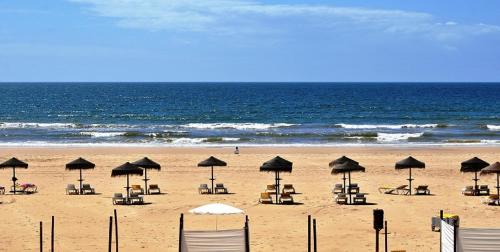 einen Strand mit Liegestühlen und Sonnenschirmen und dem Meer in der Unterkunft Casa ao Mar in Monte Gordo