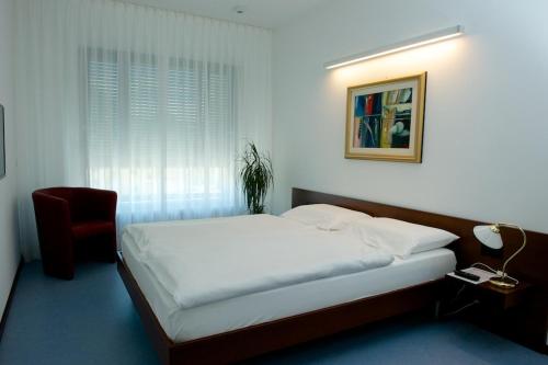 a bedroom with a bed and a chair and a window at Hotel Ceresio in Lugano