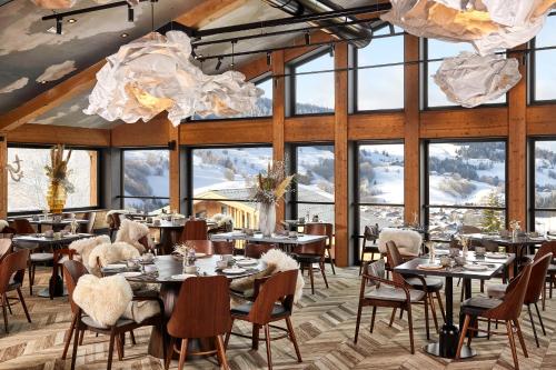 a restaurant with tables and chairs and large windows at Hôtel L'Arboisie in Megève