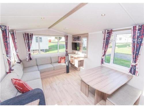 Caravana con sala de estar con mesa y sofá en Sea Break, Perran Sands, Perranporth, en Perranporth