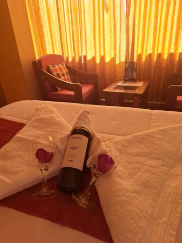 - une bouteille de vin et deux verres sur le lit dans l'établissement Chaska valle Inn, à Urubamba