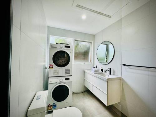 baño blanco con lavadora y lavamanos en Charming Granny Flat Conveniently Located near Knox Shopping Center, en Wantirna South