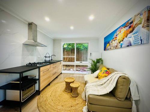 sala de estar con sofá y cocina en Charming Granny Flat Conveniently Located near Knox Shopping Center, en Wantirna South