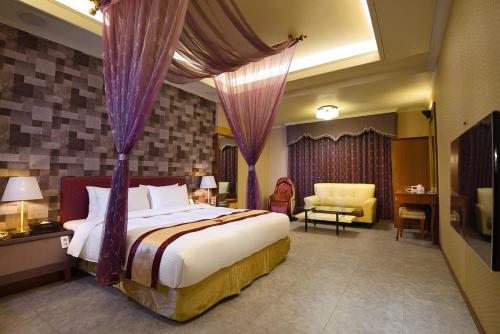 a bedroom with a large bed with purple drapes at Summer House Motel in Tainan