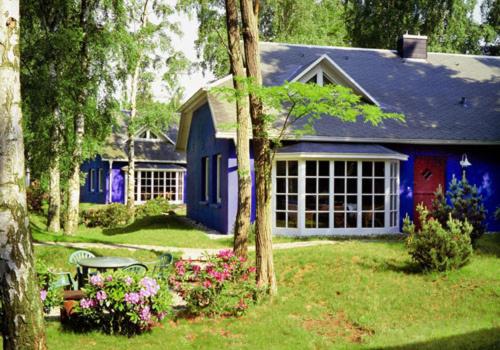 ein blaues Haus mit einem Tisch und Blumen im Hof in der Unterkunft Strandhäuser Blankenfohrt in Ückeritz