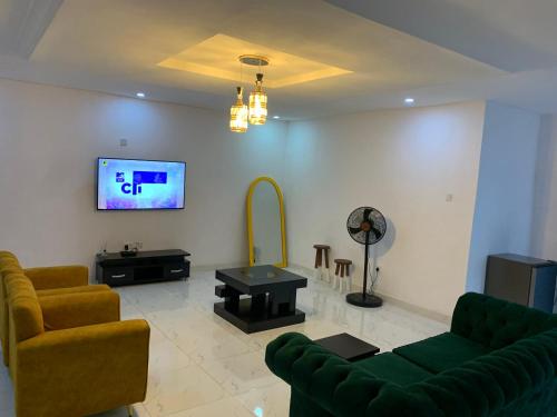 ein Wohnzimmer mit einem Sofa und einem TV an der Wand in der Unterkunft Charming & Cozy 1-BDR Apt - Mini Flat - 247 Power, Kitchen, Wi-Fi, DSTV, Netflix, 5 mins from the Airports in Ikeja