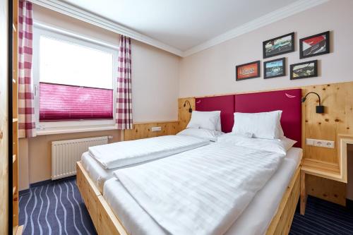 a bedroom with a large bed with a red headboard at Hotel Alpina in Obertauern