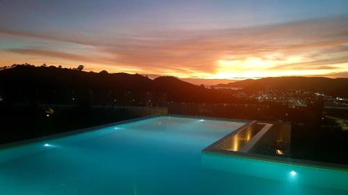 een zwembad bovenop een gebouw met een zonsondergang bij VILLA VALITO in Kuta Lombok