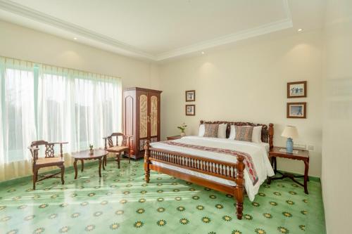 um quarto com uma cama, uma mesa e cadeiras em Villa Kouga em Pondicherry