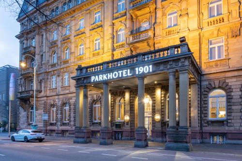 un bâtiment avec une voiture garée devant lui dans l'établissement Parkhotel 1901 Mannheim, à Mannheim