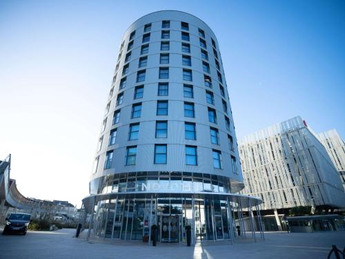 un grand bâtiment en verre dans une ville dans l'établissement Novotel Angers Centre Gare, à Angers