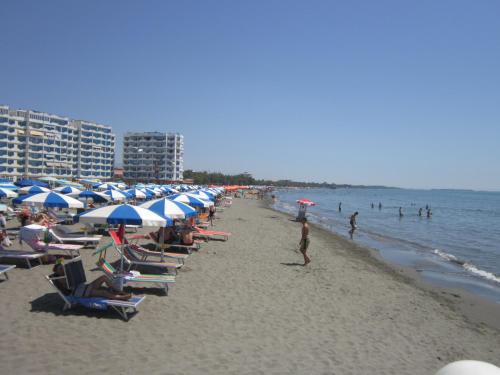 een strand met stoelen en parasols en mensen in het water bij Hotel Demar in Shëngjin