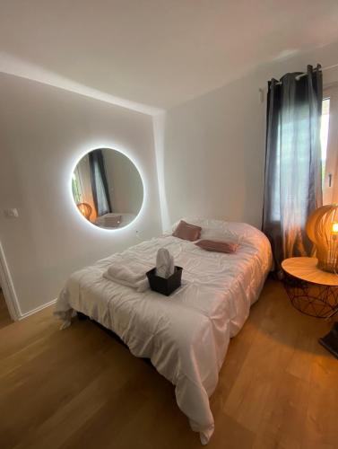 a bedroom with a bed with a round mirror at Appartement 59m2 professionnel ou familial Saint Quentin en Yvelines in Montigny-le-Bretonneux