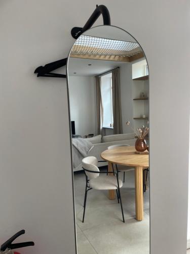 a living room with a table and a mirror at L'Apothèque - Résidence Le Cercle in Marche-en-Famenne