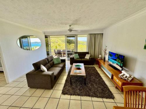 ein Wohnzimmer mit einem Sofa und einem TV in der Unterkunft Poinciana 105 in Hamilton Island