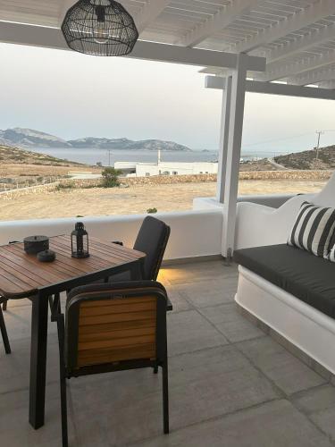 een patio met een tafel en een bank en uitzicht op het strand bij SOPHILIA SUITES in Koufonisia