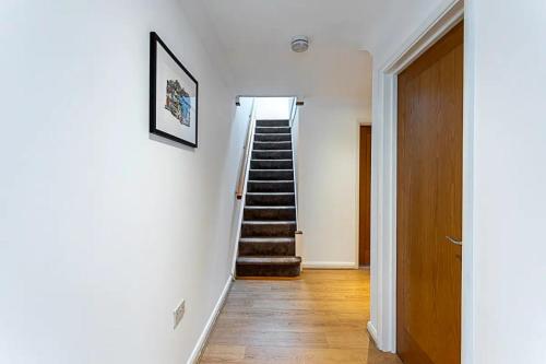 a hallway with stairs in a home with white walls at Light and airy upside down house in Hackney in London