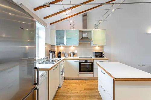 a kitchen with white cabinets and a wooden floor at Light and airy upside down house in Hackney in London