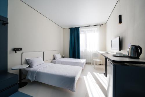 a white room with two beds and a desk at Ultramarinn Hotel in Odesa