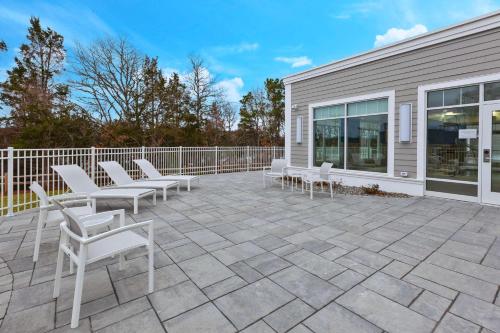 a patio with white chairs and a fence at Hampton Inn Cape Cod Canal in Buzzards Bay