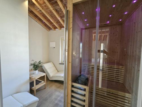 een kamer met een glazen douche en een witte stoel bij Il Tiglio Jacuzzi&Sauna in Lucca