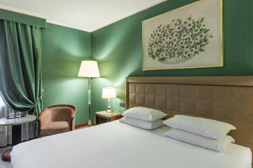 1 dormitorio con cama y pared verde en Doria Grand Hotel, en Milán