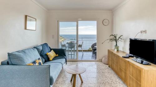 a living room with a blue couch and a television at Can Estrellas, appartement d'exception sur la mer in Roses