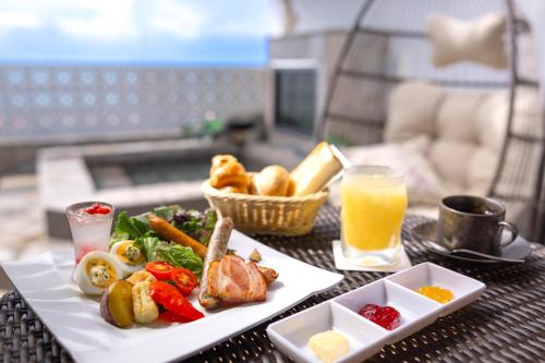 une table avec une assiette de nourriture et un verre de jus d'orange dans l'établissement Hotel Noir Blanc, à Shizuoka