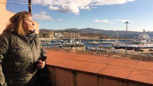 a woman standing on a ledge looking at a marina at locanda genovese 20 in La Maddalena