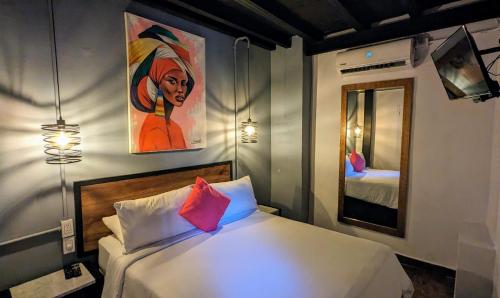 een slaapkamer met een bed met een schilderij aan de muur bij Maloka Boutique Hostel in Cartagena