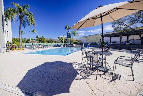 uma mesa e cadeiras com um guarda-sol ao lado de uma piscina em La Quinta Inn by Wyndham Tampa Near Busch Gardens em Tampa