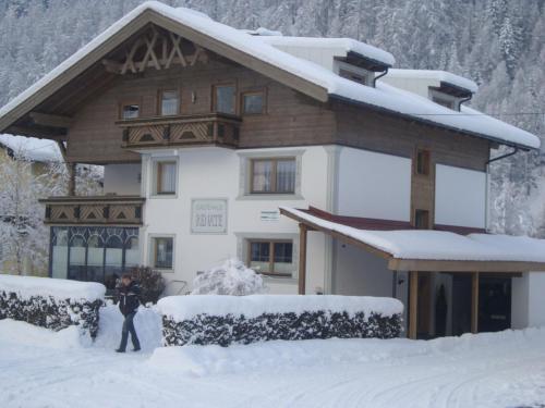 a person standing in the snow in front of a house at Gästehaus Renate in Längenfeld