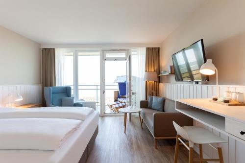 ein Hotelzimmer mit einem Bett und einem Wohnzimmer in der Unterkunft Wyn. Strandhotel Sylt in Westerland