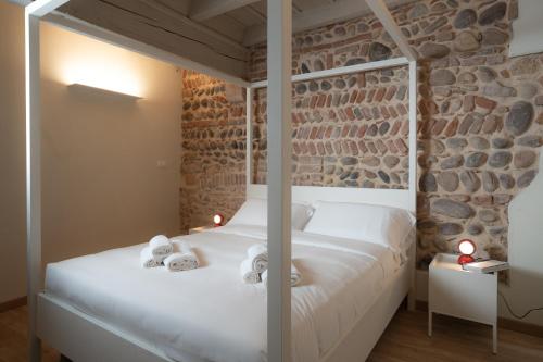 a bedroom with a white bed and a stone wall at Verona Design in Verona