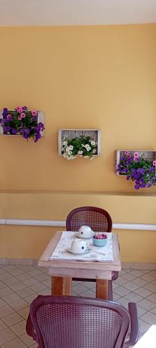 een tafel met twee stoelen en bloemen aan een muur bij Affittacamere Casa del Sole in Cala Gonone