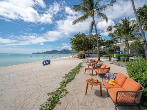 una playa con sillas y mesas y el océano en OZO Chaweng Samui, en Chaweng