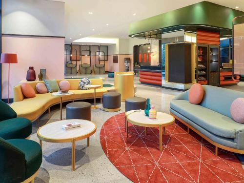 sala de estar con sofás, mesas y TV en ibis Styles Jakarta Tanah Abang, en Yakarta