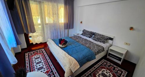 - une chambre avec un lit doté d'une couverture bleue et d'une fenêtre dans l'établissement Casa Giubega, à Buşteni