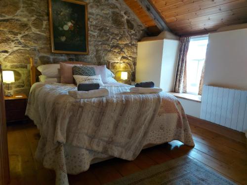 1 dormitorio con 1 cama grande en una pared de piedra en Kitts Cottage Redruth, en Redruth