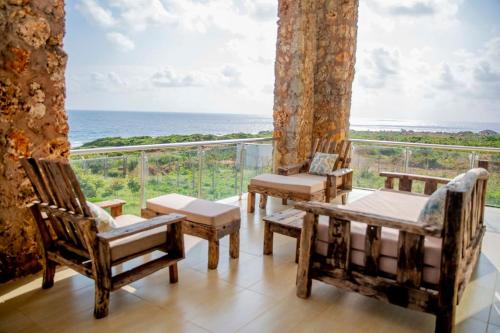 a room with chairs and a balcony with the ocean at Kumekucha Ocean View in Dar es Salaam