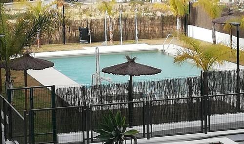 a swimming pool with umbrellas and a swimming poolvisor at Apartamento Servet, parking gratuito in Bormujos