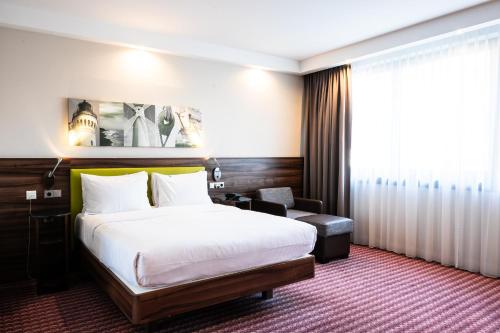 ein Hotelzimmer mit einem großen Bett und einem Stuhl in der Unterkunft Hampton by Hilton Świnoujscie in Świnoujście