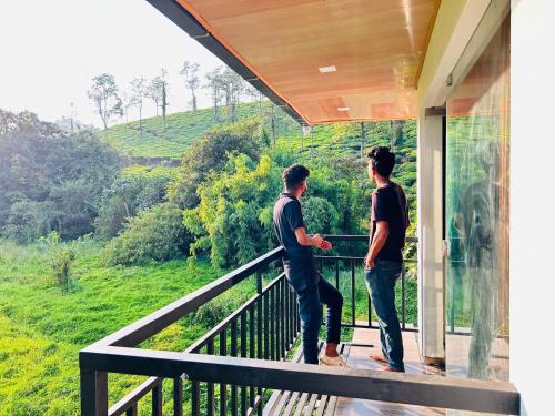 2 hommes debout sur le balcon d'une maison dans l'établissement Green view suits, à Vythiri