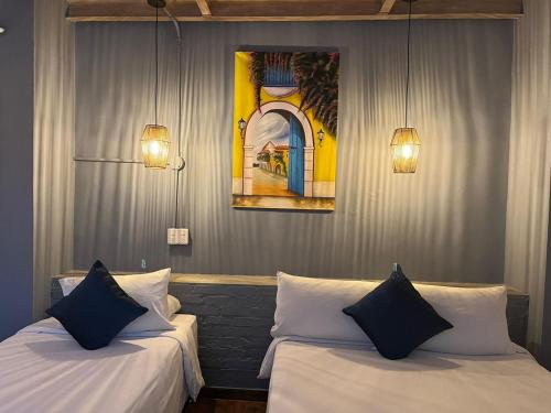 twee bedden in een kamer met twee lampen en een schilderij bij Maloka Boutique Hostel in Cartagena