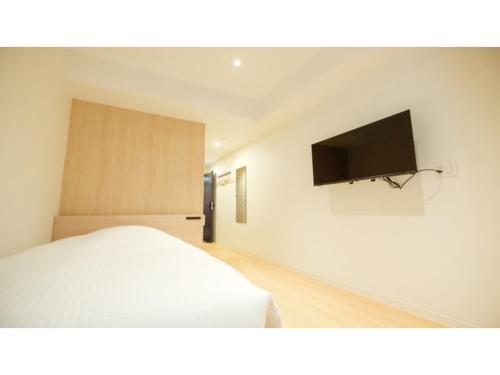 una camera con letto e TV a schermo piatto di ELE HOTEL KUZUHA- Vacation STAY 80313v a Hirakata