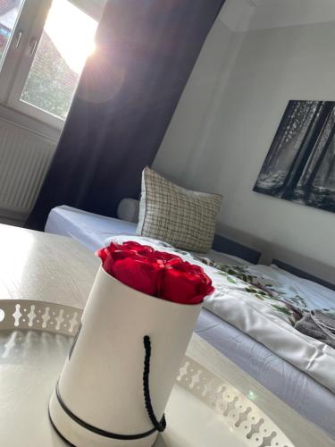 eine weiße Vase mit roten Rosen auf dem Bett in der Unterkunft Gemütliche Wohnung in der Stadt 1 in Arnstadt