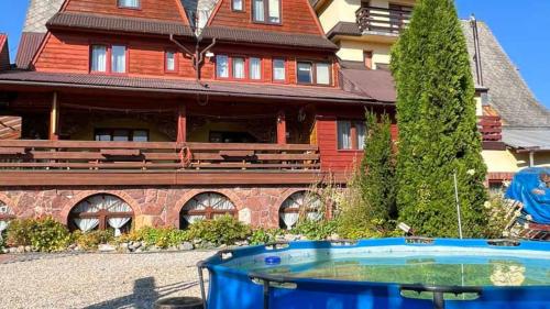 a house with a swimming pool in front of a house at Kwatery u Papieżów in Biały Dunajec